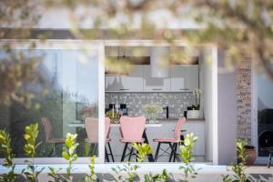 a patio with pink chairs and a table at Villa Millennium in Jezera