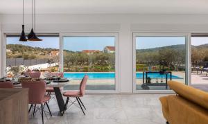 a dining room with a view of a pool through windows at Villa Millennium in Jezera