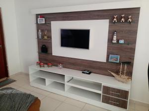 a living room with a television on a wall at Lindo sobrado a 100 m praia do Aruan. in Caraguatatuba