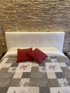 a bed with red pillows and a brick wall at Appartamenti Lucia in Andalo