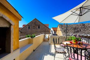 a balcony with a table and an umbrella at Luxury villa Kalalarga in the center of the town in Makarska