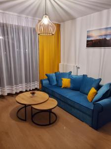 a living room with a blue couch and a table at APARTAMENT BLUE , Marynarska 8 , Sarbinowo in Sarbinowo