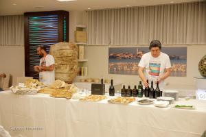 サン・ジョヴァンニ・ロトンドにあるHotel Coronaの二人の男が食べ物とワインを持ってテーブルの前に立っている