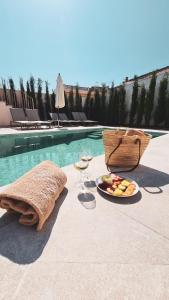 Ynaira hotel & Spa في أرياني: صحن من الفاكهة وكؤوس النبيذ بجوار حمام سباحة