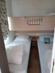 2 bedden in een kleine kamer met witte lakens en kussens bij Luxueuze stacaravan in Bredene met eigen terras en tuintje (425) in Bredene