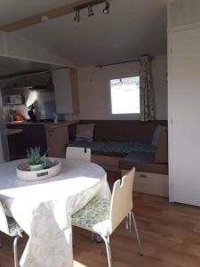 een woonkamer met een tafel en stoelen en een slaapkamer bij Luxueuze stacaravan in Bredene met eigen terras en tuintje (425) in Bredene
