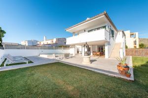 una casa bianca con un prato davanti di A perfect location villa for holidays with AC and private pool a Port de Pollença