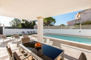 un patio esterno con tavolo e sedie accanto alla piscina di A perfect location villa for holidays with AC and private pool a Port de Pollença