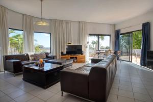 ein Wohnzimmer mit Ledersofas und einem TV in der Unterkunft Villa Paradise Beach in Giniginámar