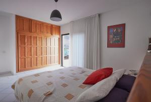 a bedroom with a bed with a red pillow on it at Villa Paradise Beach in Giniginámar