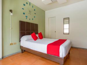 a bedroom with a bed with red pillows and a clock at Hotel Allende 104 in Chihuahua