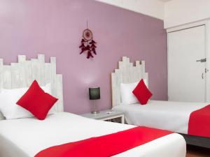 um quarto com 2 camas e almofadas vermelhas em Hotel Allende 104 em Chihuahua