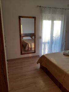 ein Schlafzimmer mit einem Spiegel, einem Bett und einem Fenster in der Unterkunft Apartment Luka in Bibinje