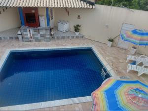 a swimming pool with two umbrellas next to a house at Casa na Barra de São Miguel in Barra de São Miguel