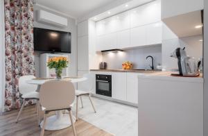 a kitchen with white cabinets and a table and chairs at Flow Apartments Toruń in Toruń
