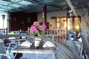 a vase of flowers sitting on a table in a restaurant at Logis Hôtel Les 3B in Nouilhan