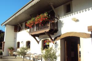 a white building with a balcony with flowers on it at Logis Hôtel Les 3B in Nouilhan
