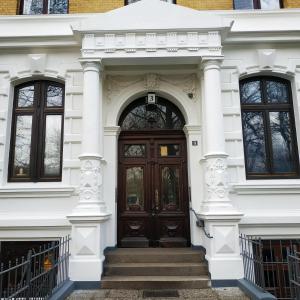 a white house with a wooden door and stairs at Apartment Alster in Hamburg