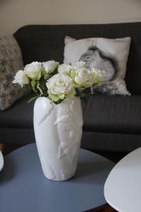 un jarrón blanco con rosas blancas sobre una mesa en Appartement T4 - Centre de Luchon - 6 pers - Ski - Randonnée - Cure en Luchon