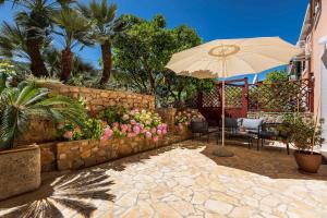 eine Terrasse mit einem Sonnenschirm, Stühlen und Blumen in der Unterkunft Holiday home in Veli Losinj 40979 in Veli Lošinj
