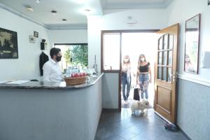 阿蒂巴亞的住宿－Pousada Vista da Pedra Atibaia，男人和两个女人和狗一起站在柜台上