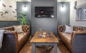 uma sala de estar com sofás de couro castanho e uma mesa em Griffin Inn em Ruthin