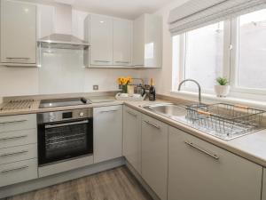 a kitchen with white cabinets and a sink at Pebble Cove in Morpeth