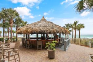 a restaurant with a straw umbrella and chairs and the beach at Calypso Resort and Towers #801-W by Book That Condo in Panama City Beach