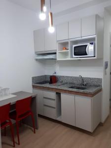 a kitchen with white cabinets and a sink and a microwave at Flat Completo in Cotia