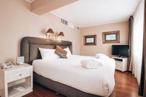 a bedroom with a large white bed and a television at Suites del Bosque Hotel in Lima +82 photos