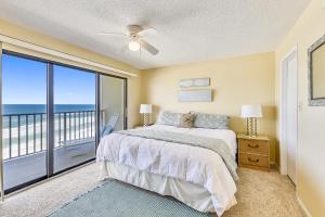 a bedroom with a bed and a balcony with the ocean at Commodore Resort #703 by Book That Condo in Panama City Beach +55 photos