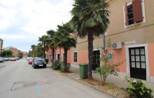 eine Straße mit Palmen und einem Auto neben einem Gebäude in der Unterkunft Apartment in Porec/Istrien 36967 in Poreč