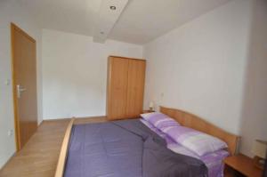a bed in a room with purple pillows on it at Apartment in Vrbnik/Insel Krk 36796 in Vrbnik