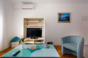 ein Wohnzimmer mit einem Tisch, einem Stuhl und einem TV in der Unterkunft Apartments in Vrbnik - Insel Krk 36771 in Vrbnik