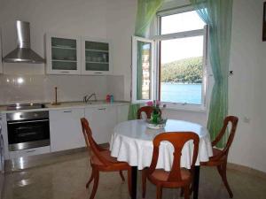 eine Küche mit einem Tisch und Stühlen sowie einem Fenster in der Unterkunft Apartment in Rabac 16989 in Rabac