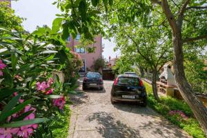 two cars parked on a street with trees and flowers at Apartment in Crikvenica 14098 in Dramalj