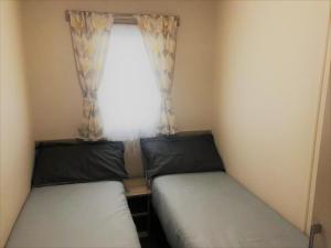 two beds in a small room with a window at Ash Standard Holiday Home in Chapel Saint Leonards