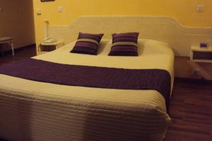 a large bed in a hotel room with two pillows at Logis Hôtel Les 3B in Nouilhan