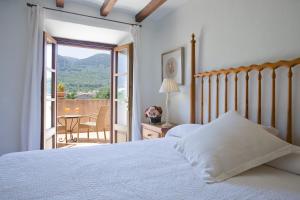 a bedroom with a bed and a balcony with a table at Finca Ca'n Quatre in Sóller