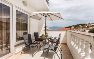 a balcony with a table and chairs and an umbrella at Apartments in Vrbnik/Insel Krk 36005 in Vrbnik