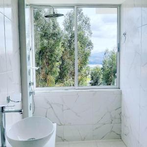 Baño blanco con ventana, bañera y lavabo en Santelmo Casa Hotel Boutique, en Paipa