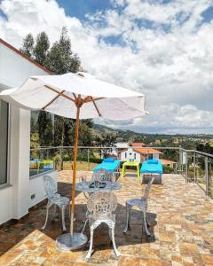 un patio con mesa, sillas y sombrilla en Santelmo Casa Hotel Boutique, en Paipa