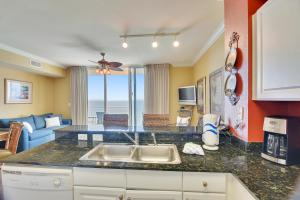 a kitchen with a sink and a living room at Tidewater Beach Resort #2014 by Book That Condo in Panama City Beach