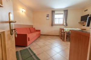 a living room with a red couch and a kitchen at Baita Nicoló in Livigno