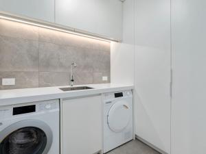 a white kitchen with a washing machine and a sink at The Bunker Alpha B in Queenstown +13 photos