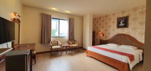 a hotel room with a bed and a desk and a television at Hoang Yen Hotel in Thuan An