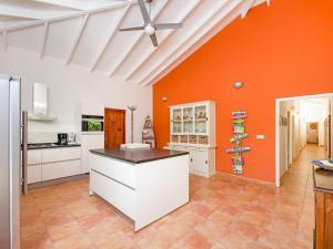 a large kitchen with orange walls and white cabinets at Pool Villa near Jan Thiel in Jan Thiel