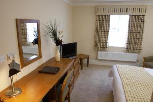 a room with a desk and a bedroom with a bed at The Barns Hotel in Cannock