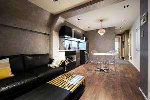 een woonkamer met een zwarte bank en een tafel bij Real Life SANGENJAYA in Tokyo