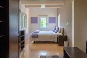 Un dormitorio con una cama con almohadas moradas y una ventana en Cisco Moon, en Kutchan